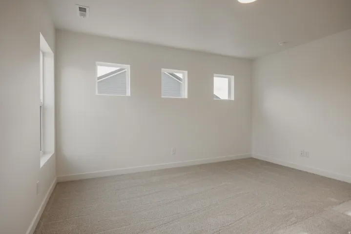 Spacious room featuring neutral carpeting, white baseboards, and bright white walls