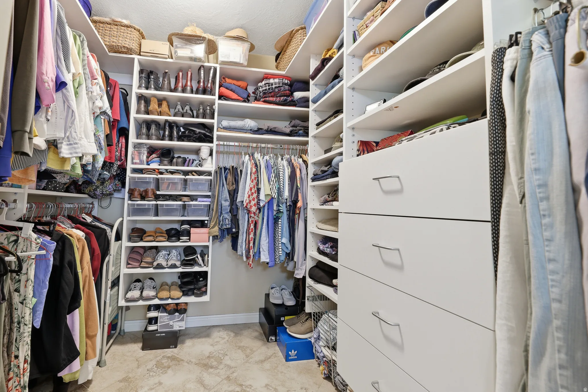 Custom closet system featuring multiple hanging rods, integrated shelving, built-in shoe racks, and full-extension drawers.
