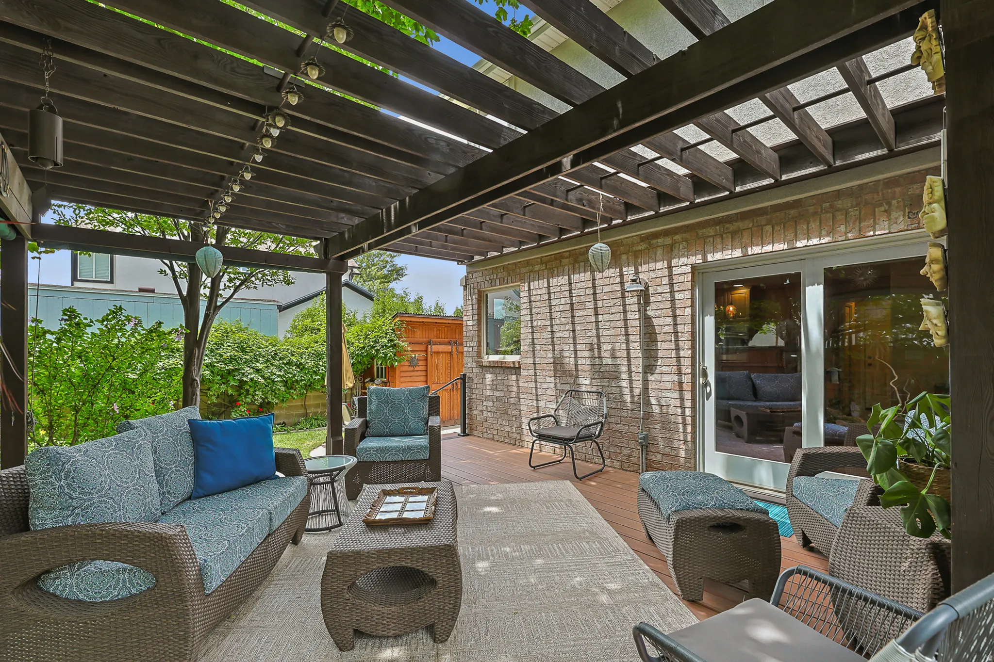 Expansive outdoor living area featuring a redwood pergola, brick exterior, and trex style decking