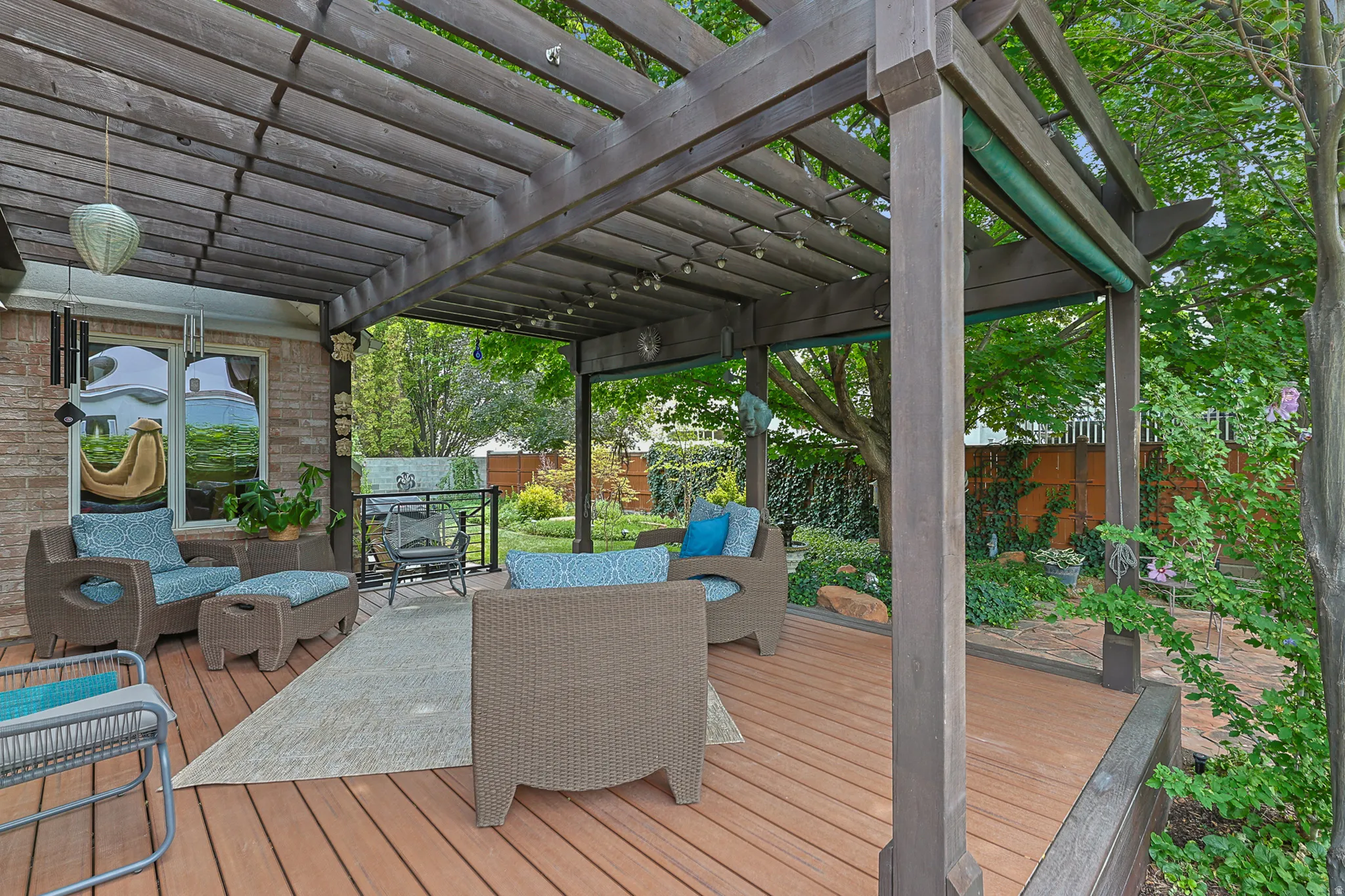 Expansive outdoor decking with a redood pergola, string lighting, and brick wall accents