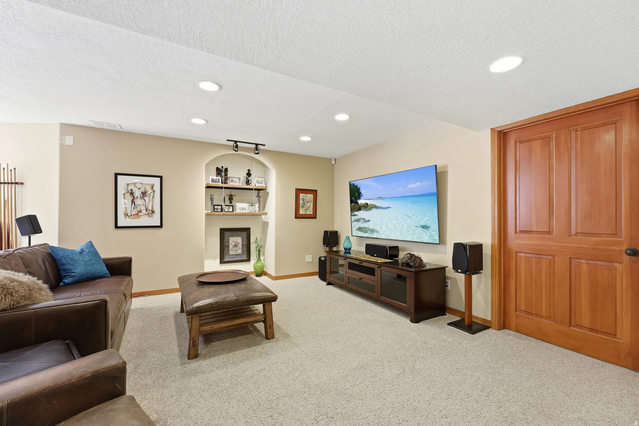 Spacious entertainment area featuring neutral-toned walls, recessed ceiling lighting, and light-colored carpeting