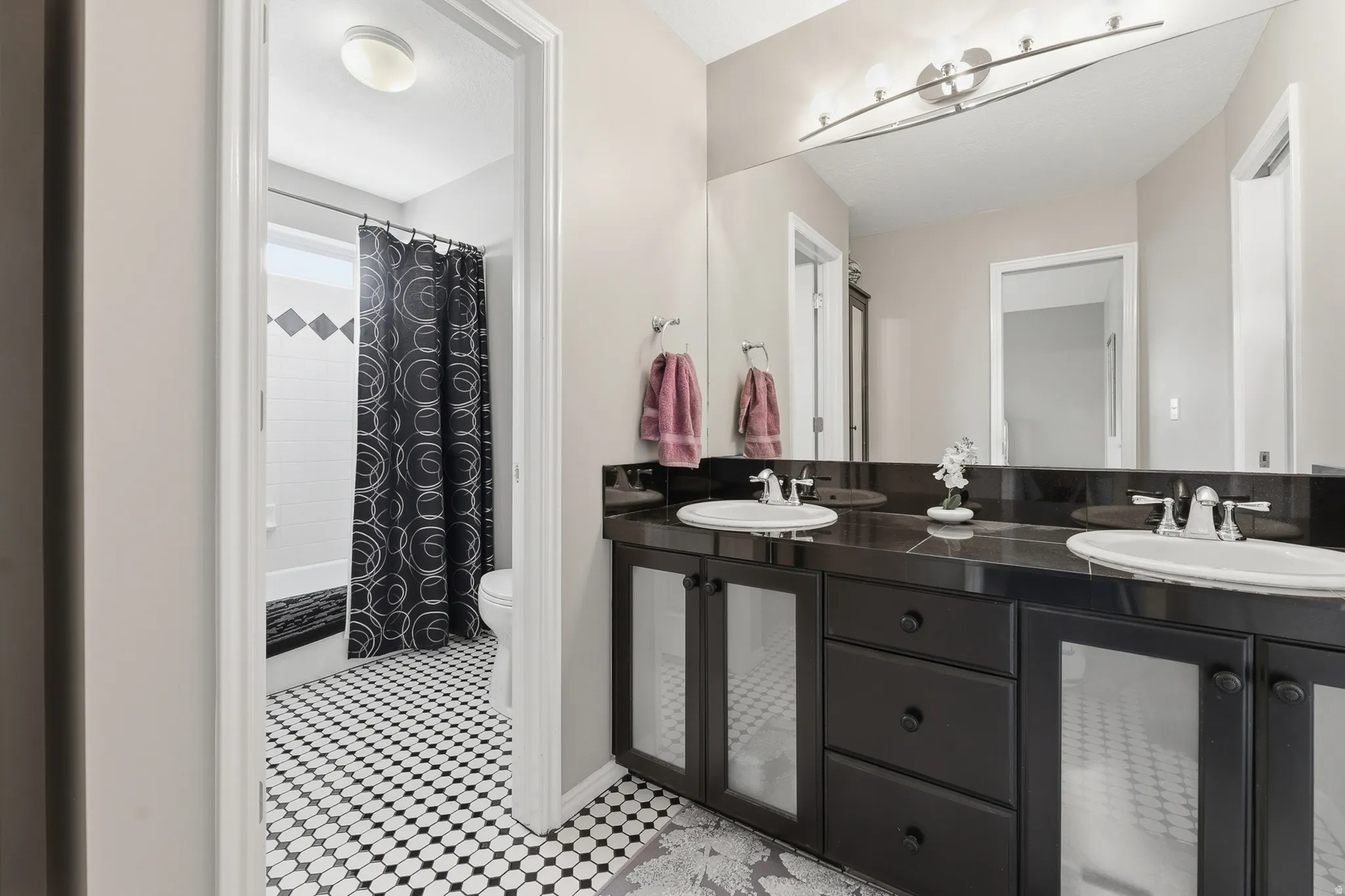 Bathroom featuring a dual vanity, two undermount sinks, and a large wall-mounted mirror