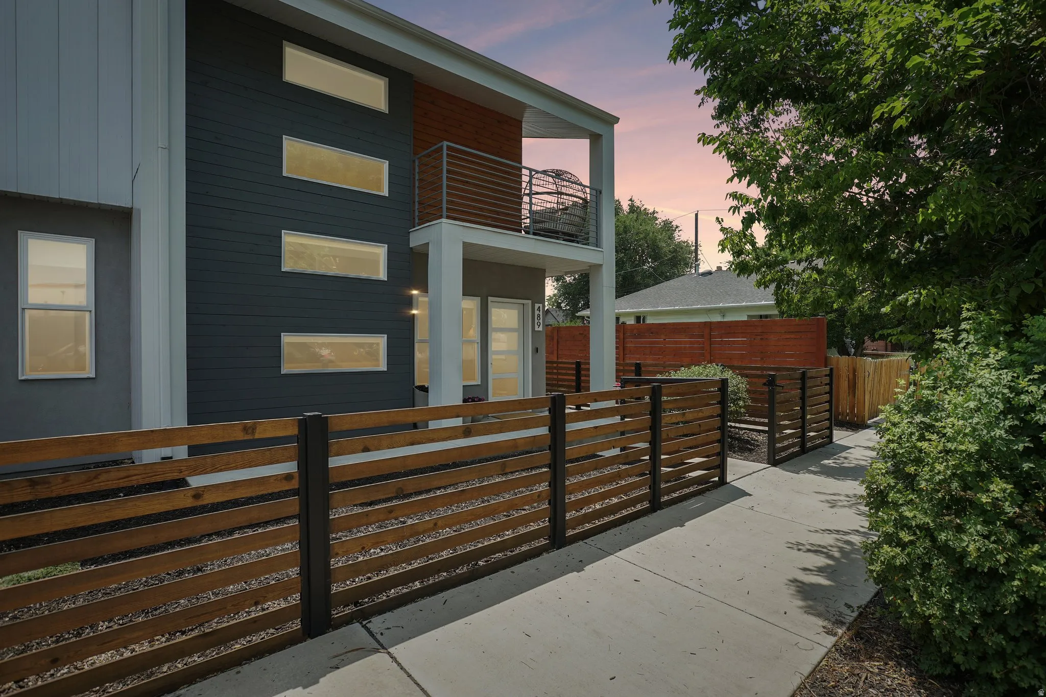 Contemporary exterior featuring dark siding with horizontal accents, multiple rectangular windows, and a second-story balcony