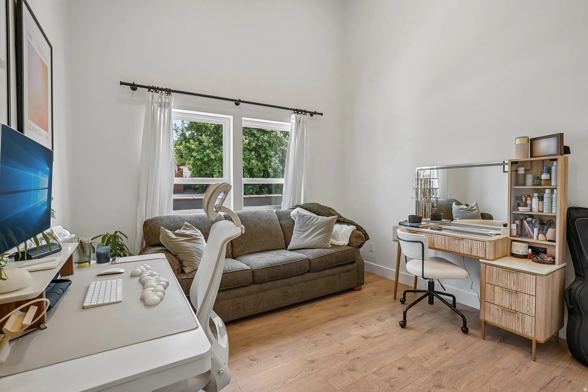 Spacious room featuring light wood-finish flooring, high ceilings, and ample natural light from multiple windows