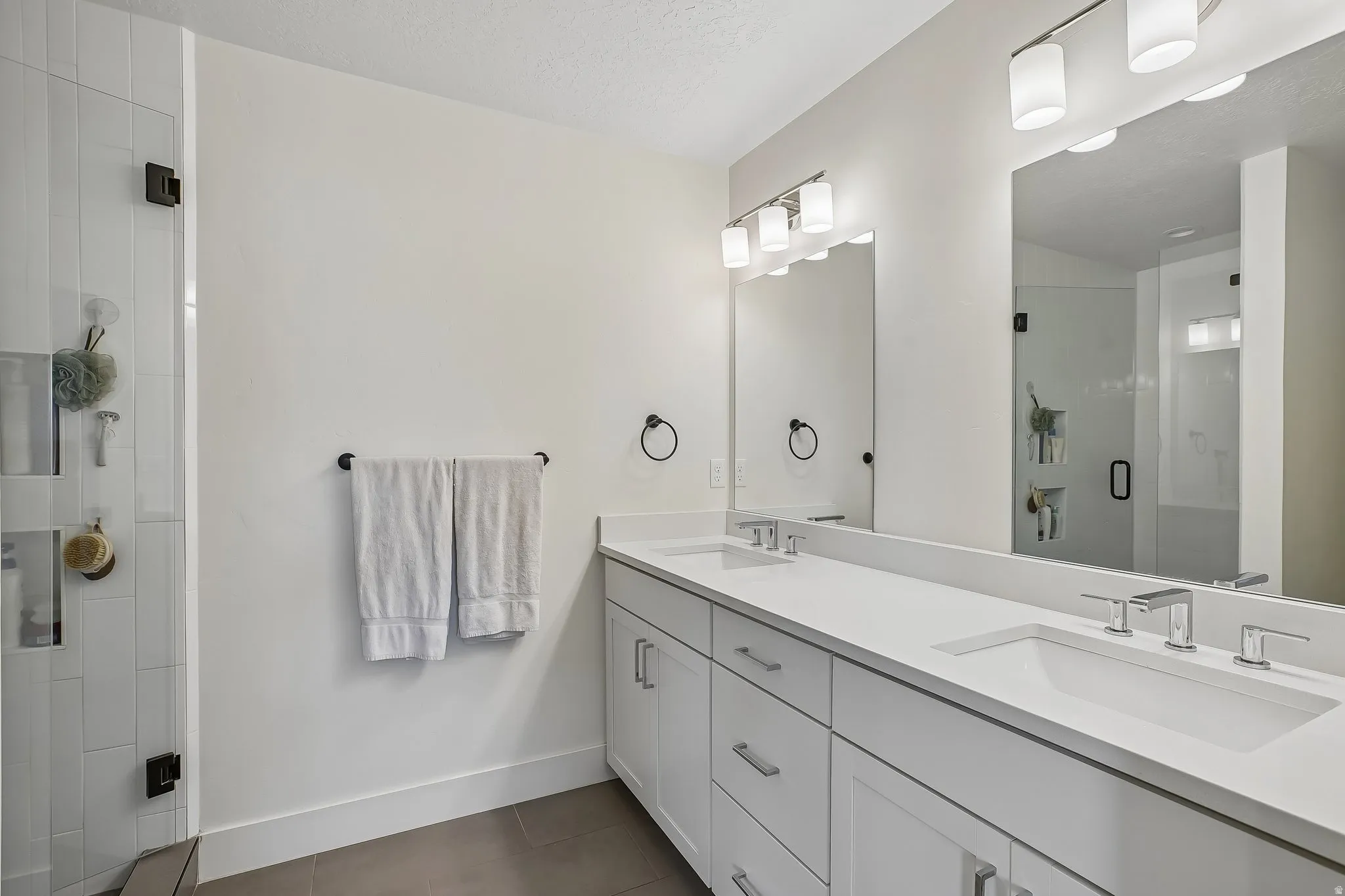 Dual vanity with white cabinetry, integrated sinks, and polished chrome fixtures