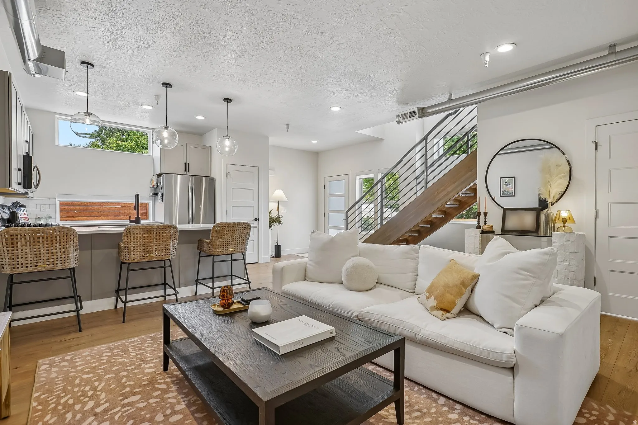 Open-concept living space featuring a modern kitchen with a large island, stainless steel appliances, and pendant lighting