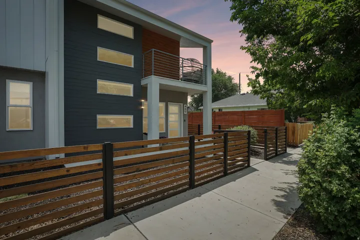 Contemporary exterior featuring dark siding with horizontal accents, multiple rectangular windows, and a second-story balcony