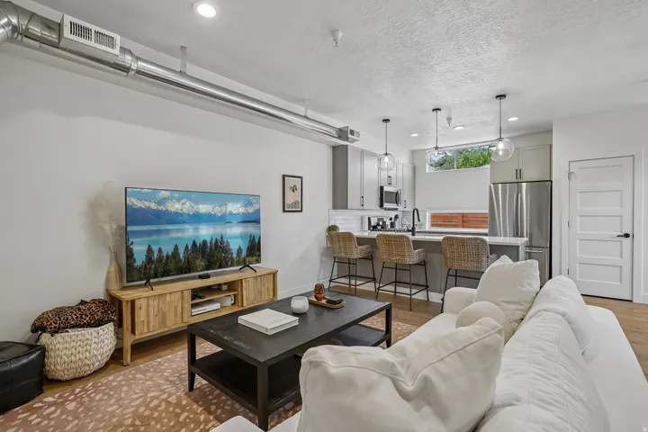 Open-concept living space featuring wood-finish flooring, recessed lighting, and exposed ductwork