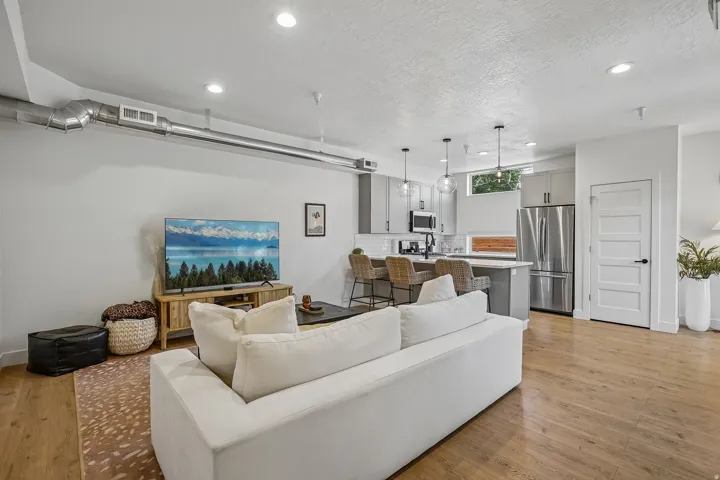 Open-concept living area featuring wood-finish flooring, recessed lighting, and exposed ductwork
