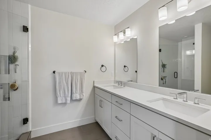 Dual vanity with white cabinetry, integrated sinks, and polished chrome fixtures