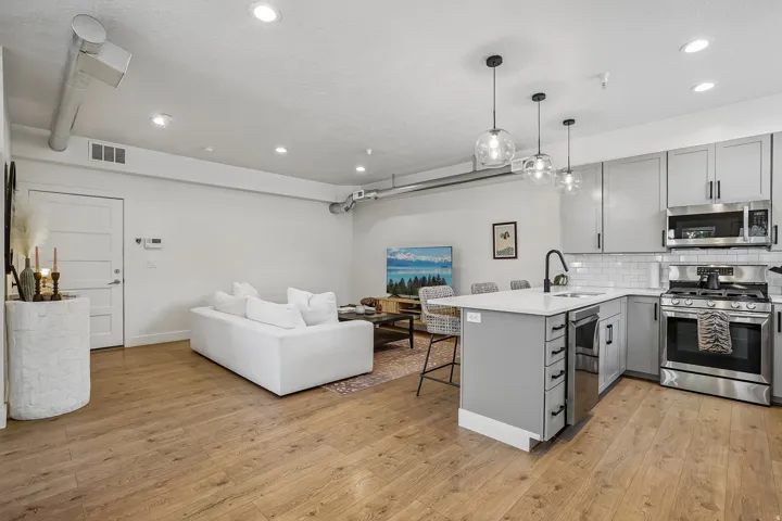 Open-concept living space featuring wood-finish flooring, recessed lighting, and exposed ductwork