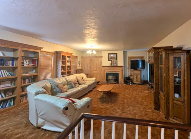 Spacious living area featuring extensive built-in wooden shelving, a wood-surround fireplace, and textured ceiling