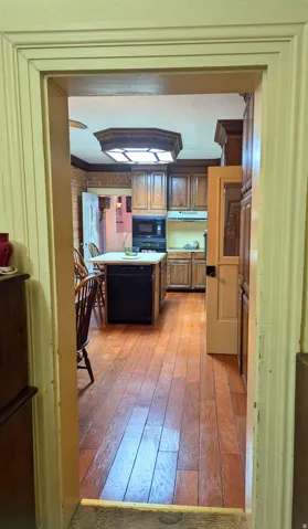 Kitchen featuring wood-finish flooring, dark wood cabinetry, a central island with integrated dishwasher, and a built-in microwave