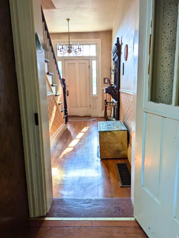 Foyer featuring hardwood flooring, a white two-panel entry door with sidelights, transom window, and a chandelier