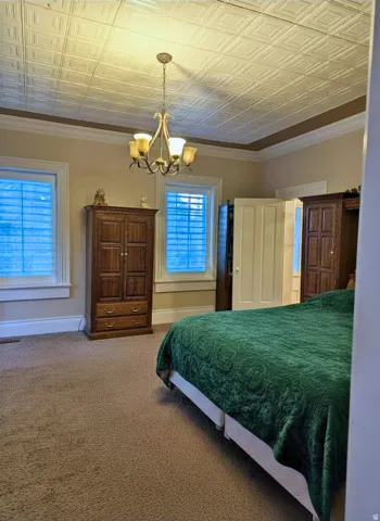 Master bedroom featuring textured ceiling panels, a decorative chandelier, and crown molding