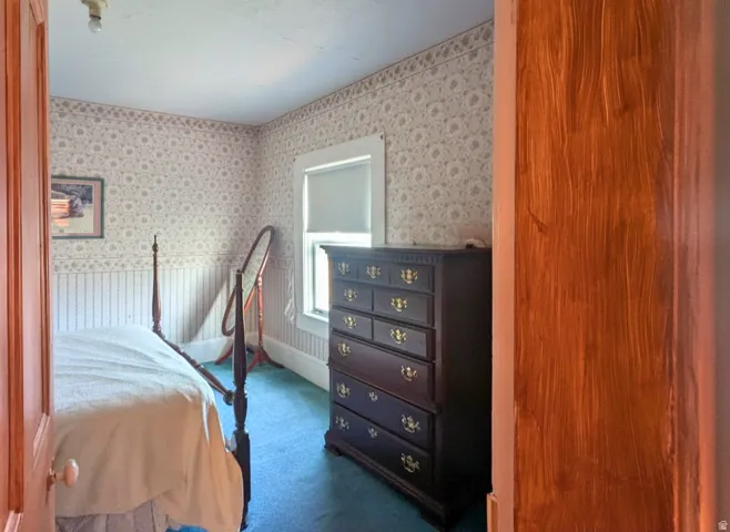 Interior room featuring patterned wallpaper, a single window, and blue carpet