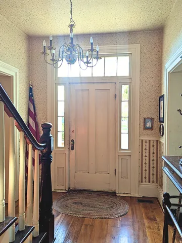 Entryway featuring a paneled door, transom window, side lights, hardwood flooring, and a chandelier