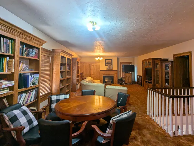 Spacious room featuring extensive built-in wood bookshelves, a central fireplace with wood mantel, and wood-finish flooring