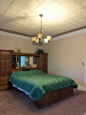 Master bedroom with a recessed panel ceiling, crown molding and a multi-arm chandelier