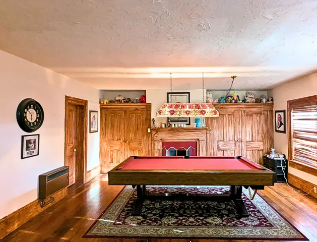 Hardwood flooring complements the fireplace with an ornate mantel and built-in cabinetry