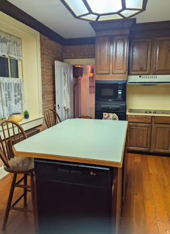 Kitchen featuring wood-finish flooring, exposed brick wall, and wood cabinetry
