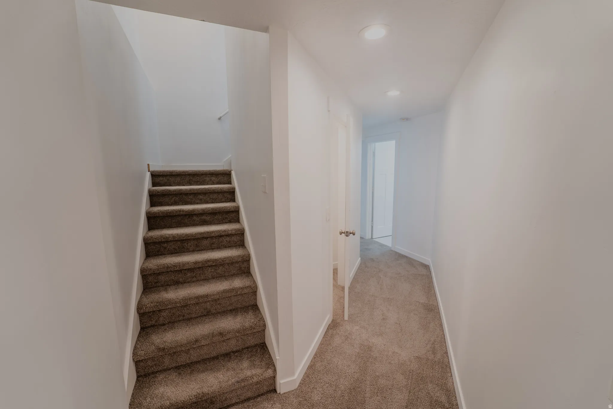 Carpeted staircase and hallway featuring recessed lighting and neutral wall finishes