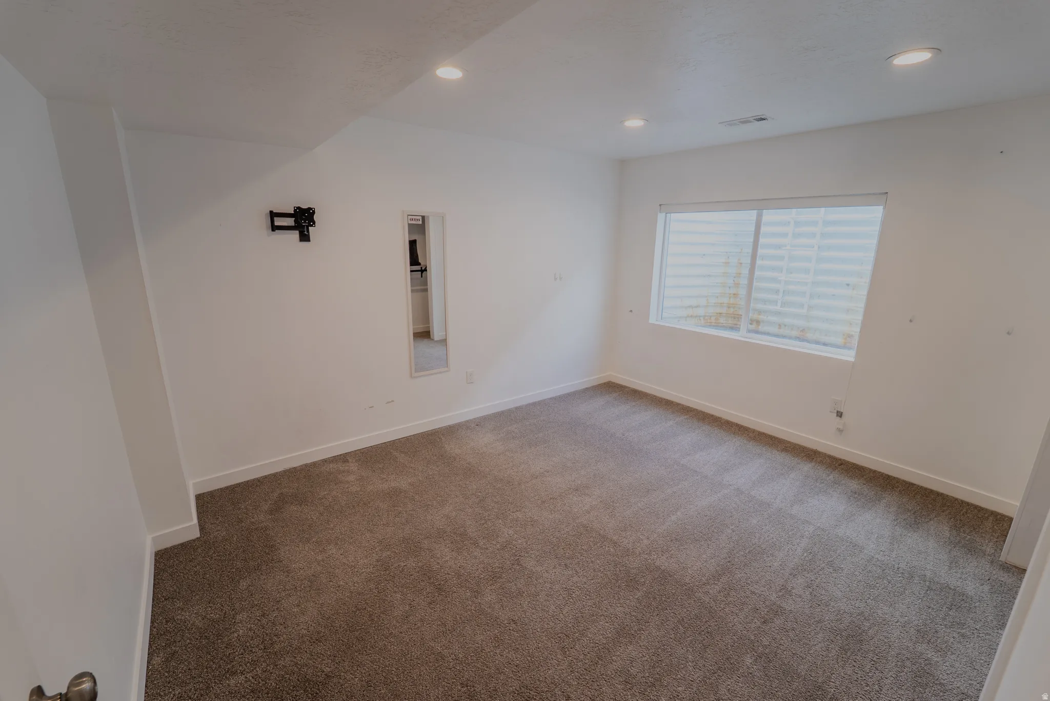 Carpeted room featuring white walls, recessed lighting, and a single window with horizontal blinds