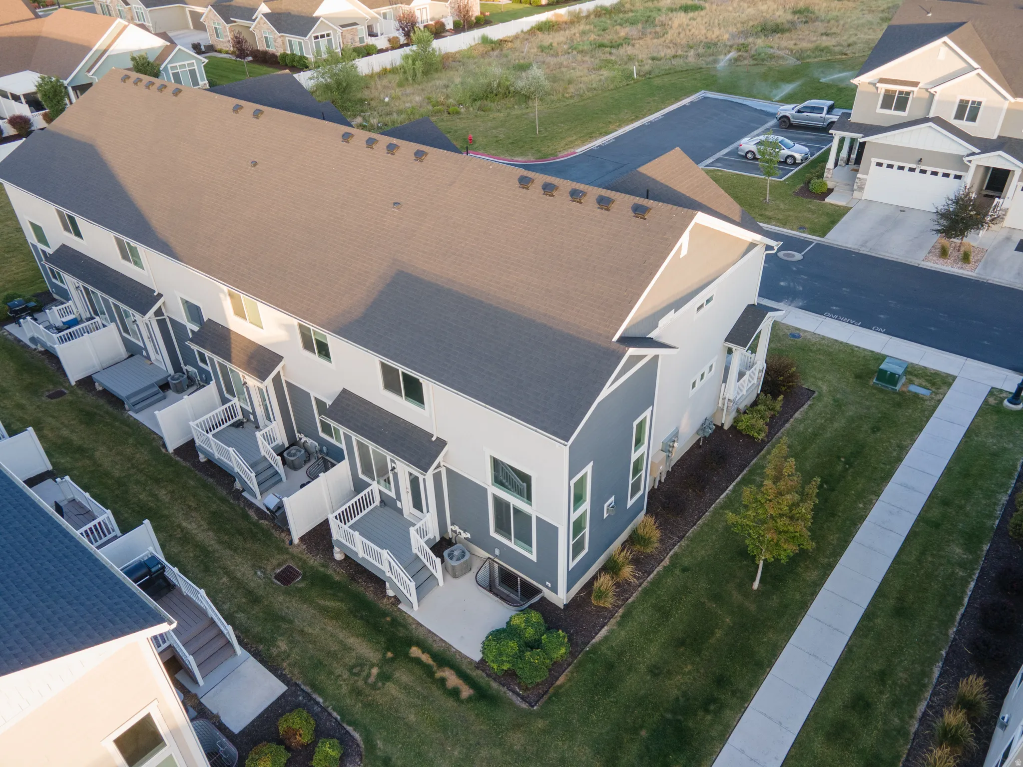 Contemporary townhouse building with a dark gray shingle roof and light-colored siding