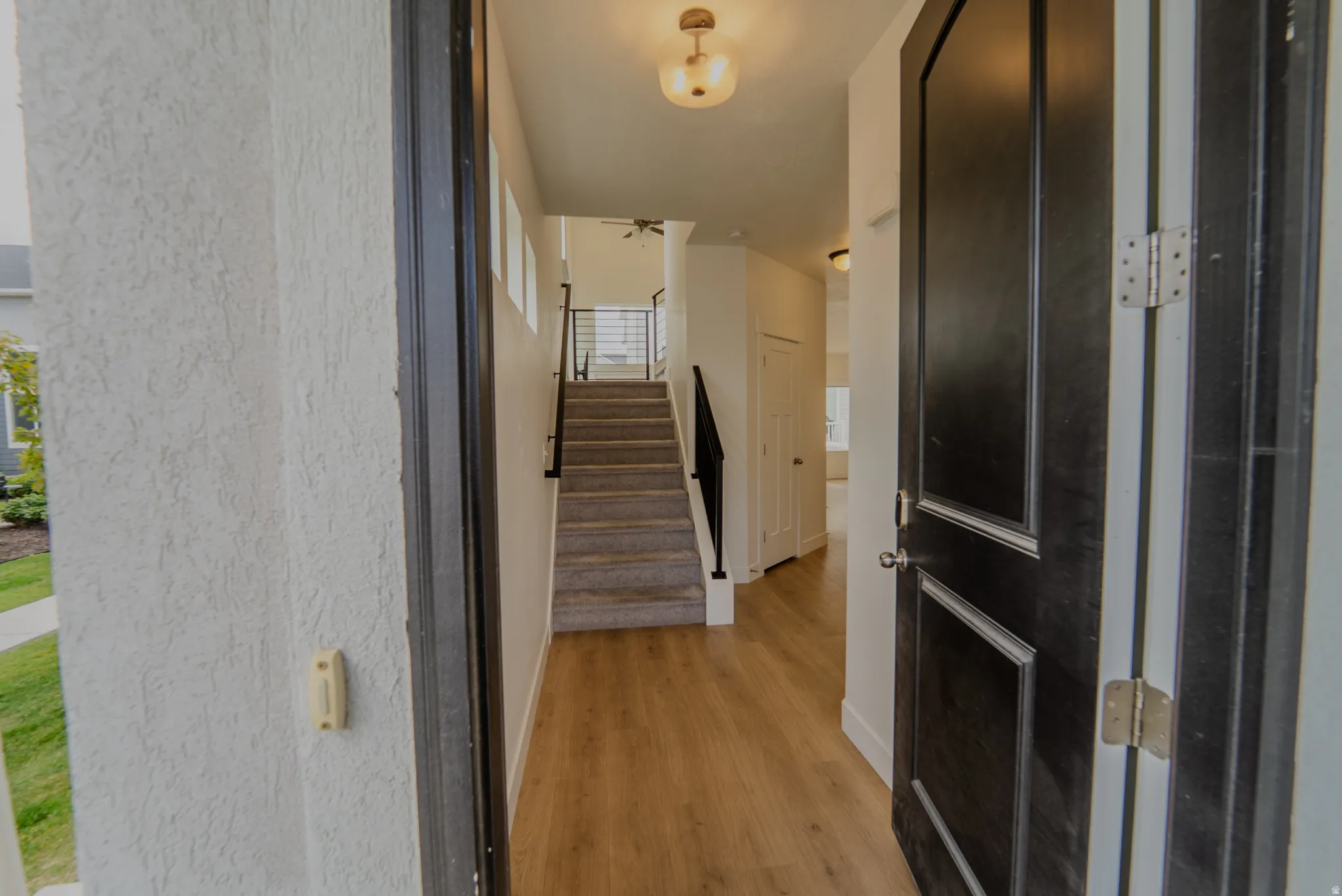 Inviting entryway featuring wood-finish flooring, a contemporary staircase with metal railings, and a panel door