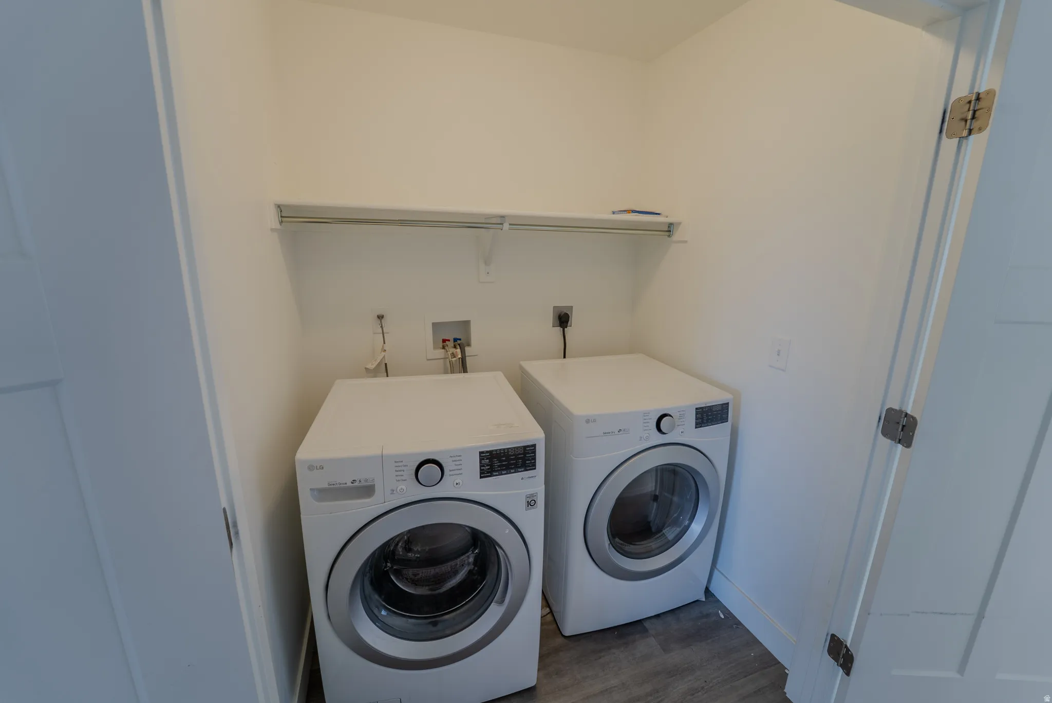 Dedicated laundry area featuring a white wire shelf, white walls, and wood-finish flooring