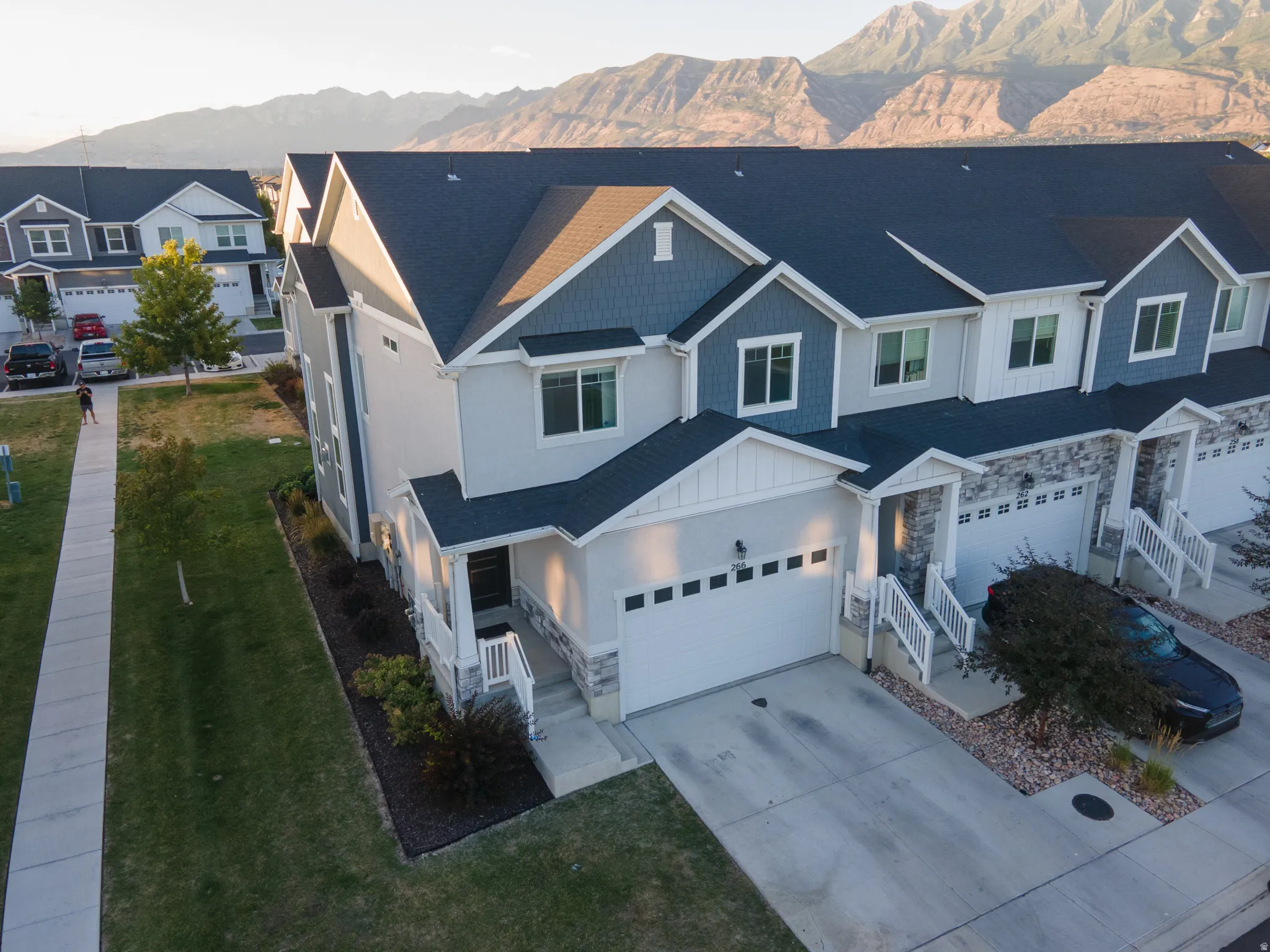 Contemporary townhome exterior featuring an attached two-car garage, stone veneer accents, and a covered entryway