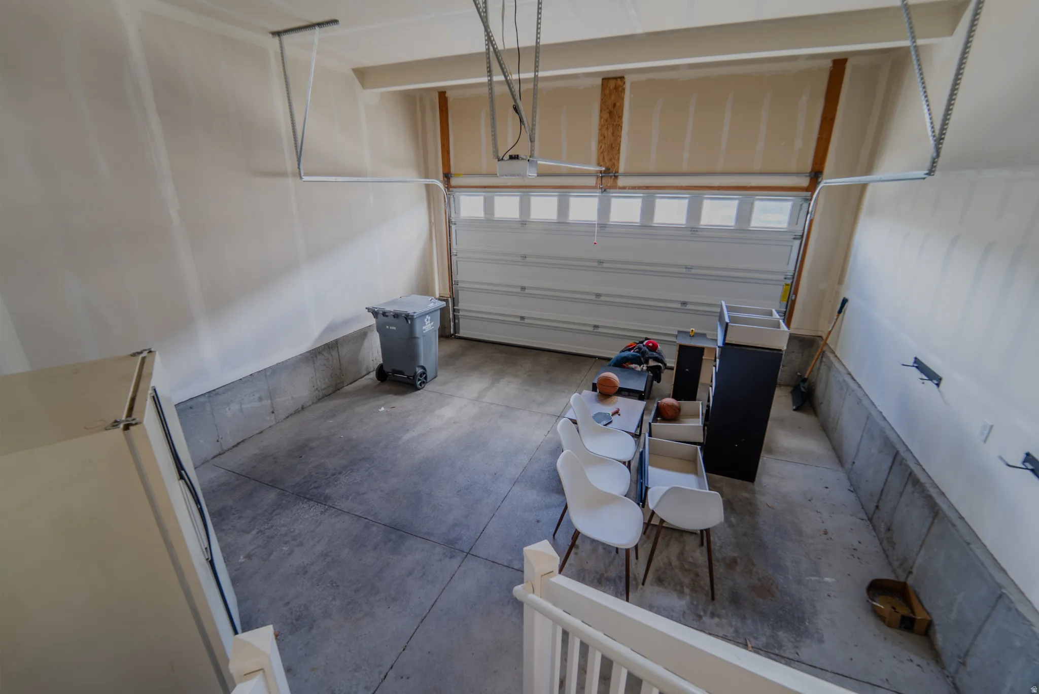 Spacious garage featuring a concrete floor, painted drywall, and an overhead garage door with upper window panels