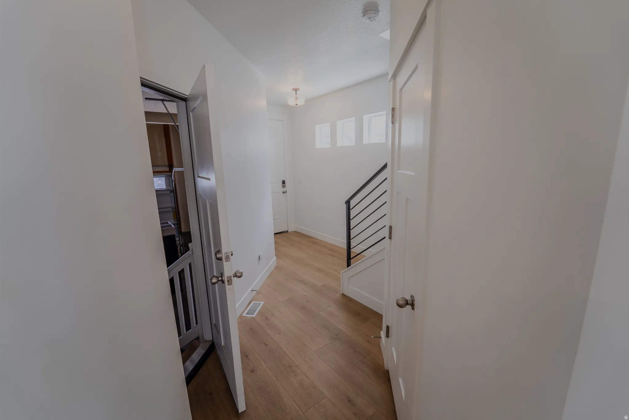 Entryway featuring light wood-finish flooring, white walls, and a contemporary staircase with black railings