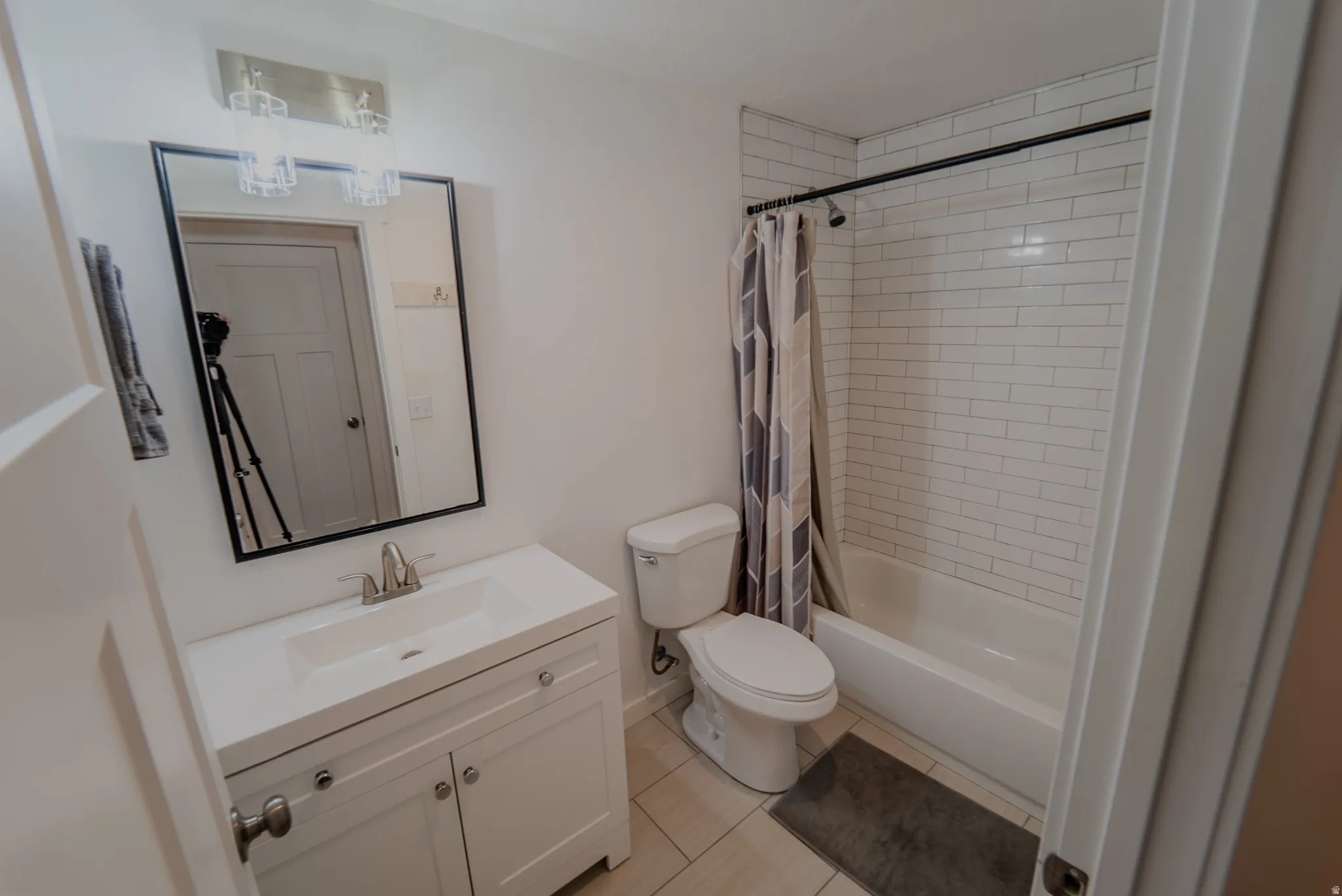 Bathroom featuring a white vanity with integrated sink, brushed nickel faucet, and a black-framed mirror