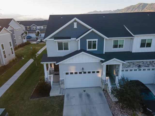 Modern townhome exterior featuring a two-car garage, contrasting siding textures, and an inviting entry porch