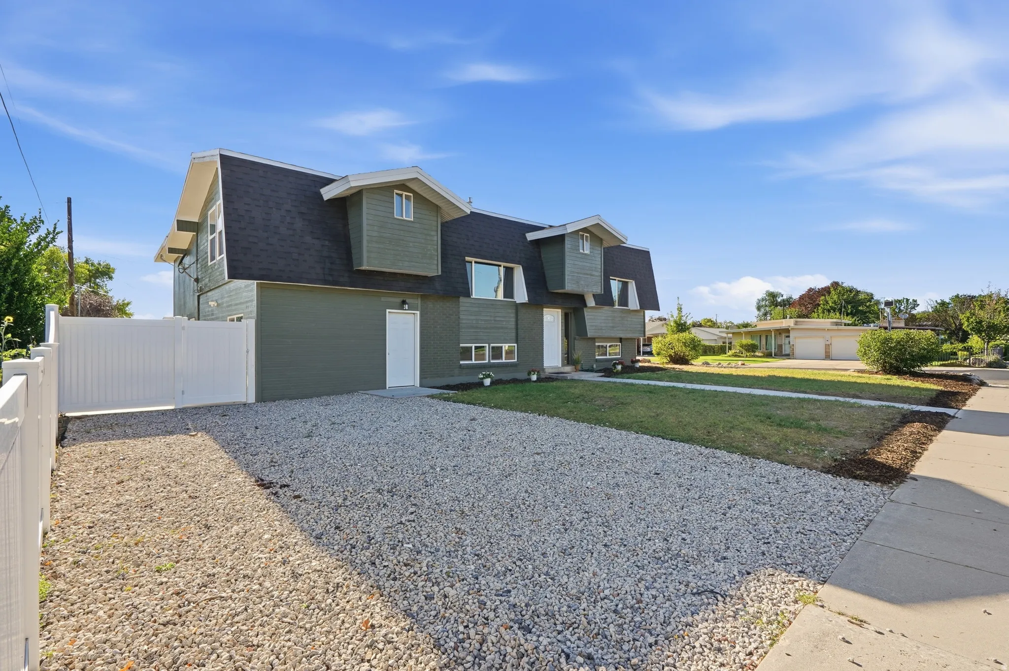 Gable-style home with dark shingle roofing, green siding, and white trim