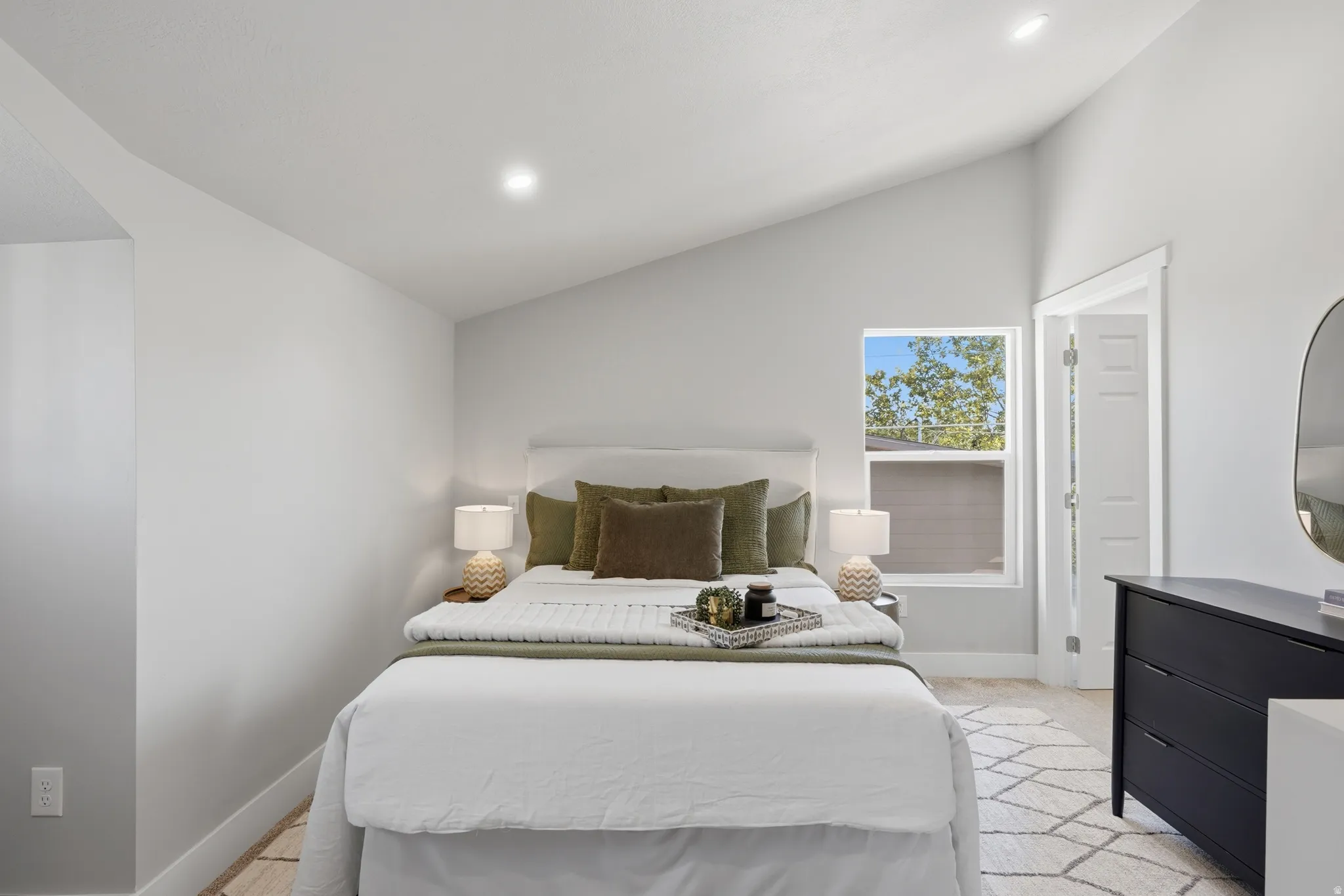 Room featuring vaulted ceiling, recessed lighting, and a single window with white trim