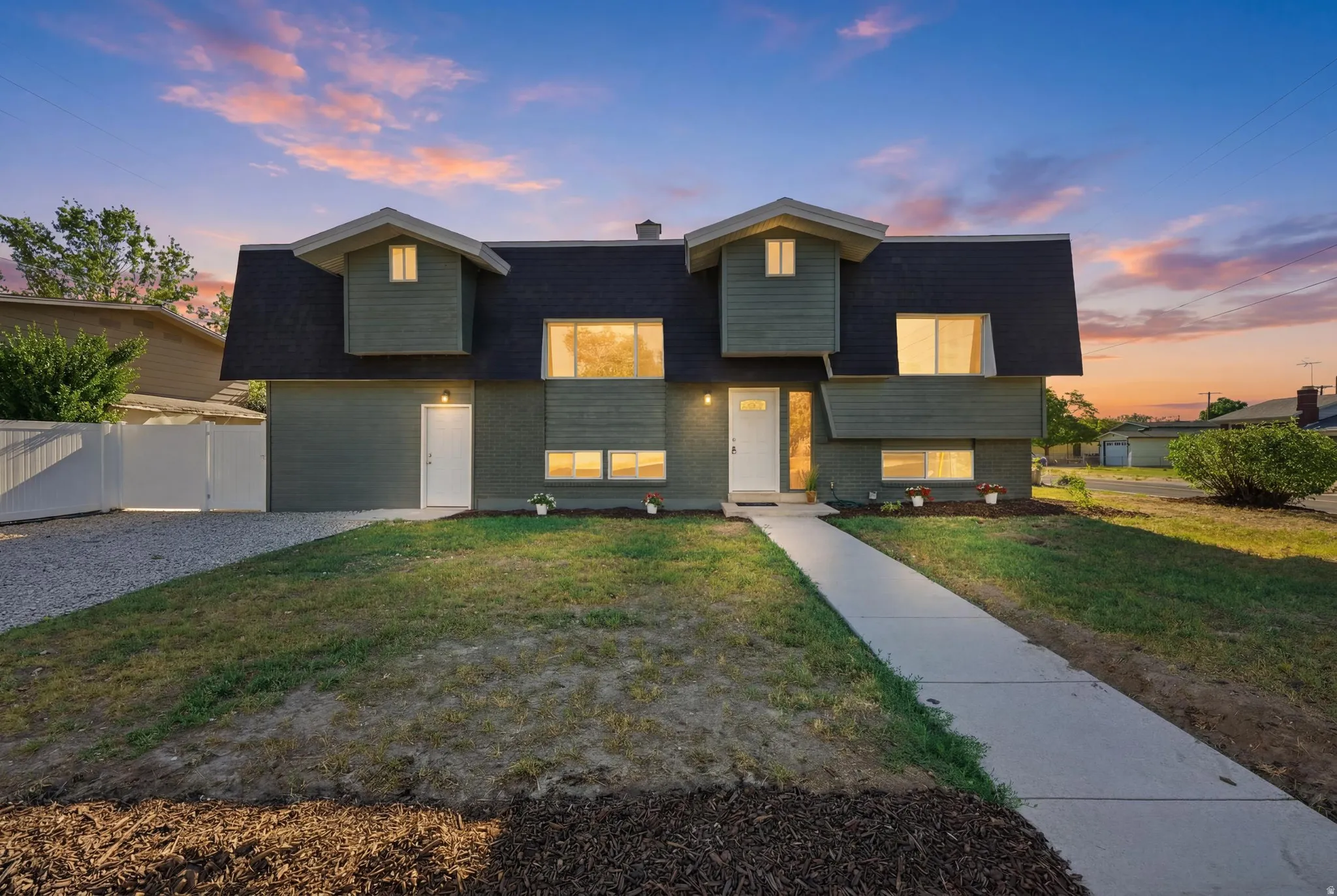 Contemporary split-level residence featuring a dark shingle roof and a muted green exterior finish