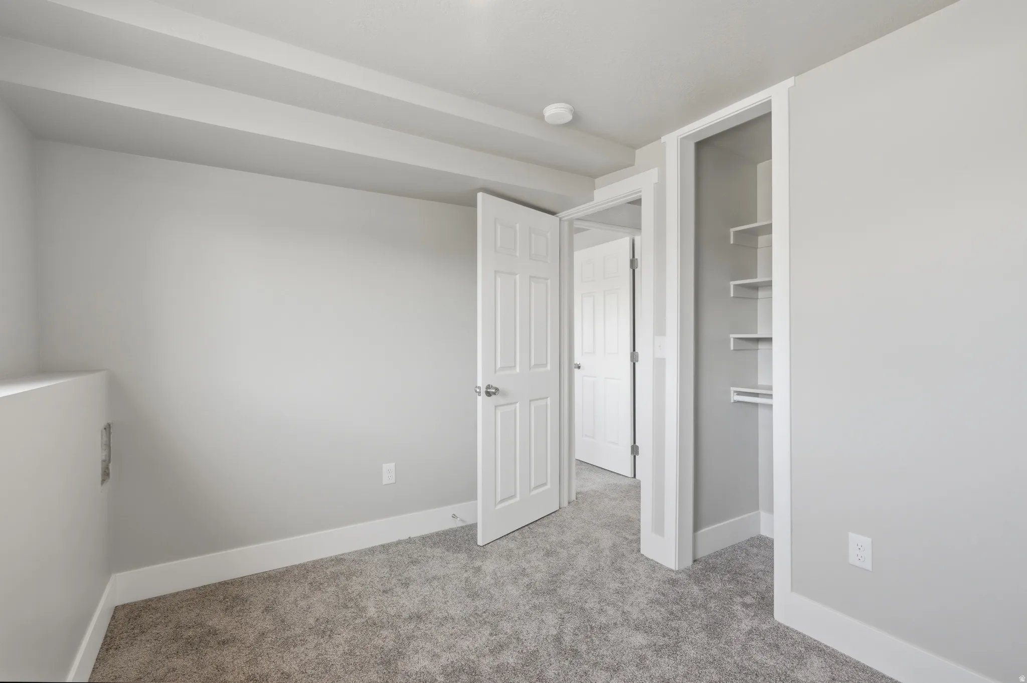 Interior space featuring light gray walls, gray carpet, white baseboards, and white ceiling trim