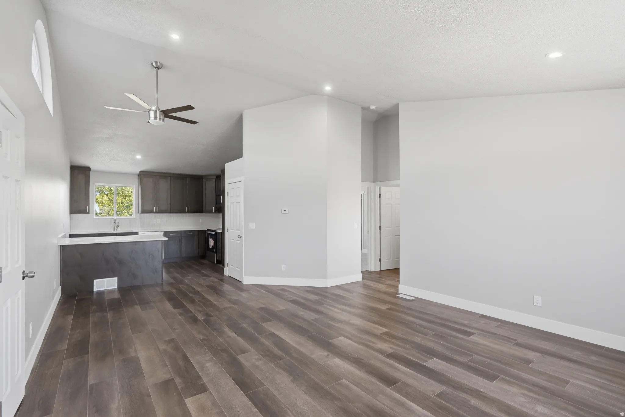 Open-concept living area featuring wood-finish flooring, vaulted ceilings, and recessed lighting