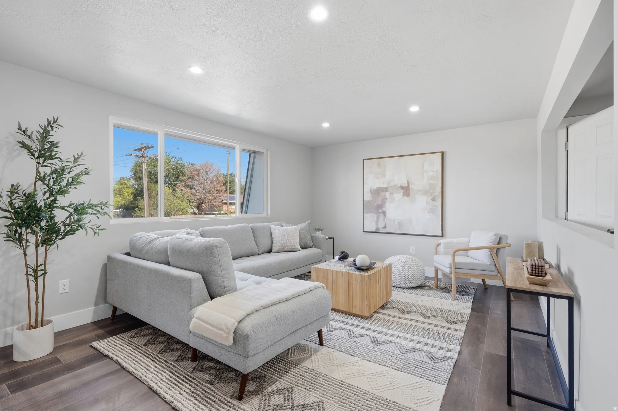 Spacious living area featuring large windows, recessed lighting, wood-finish flooring, and white baseboards