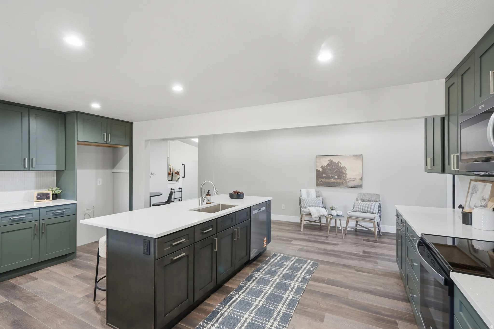 Contemporary kitchen featuring an expansive center island with an integrated sink and dishwasher, complemented by sleek white countertops