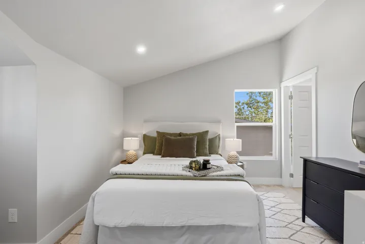 Room featuring vaulted ceiling, recessed lighting, and a single window with white trim