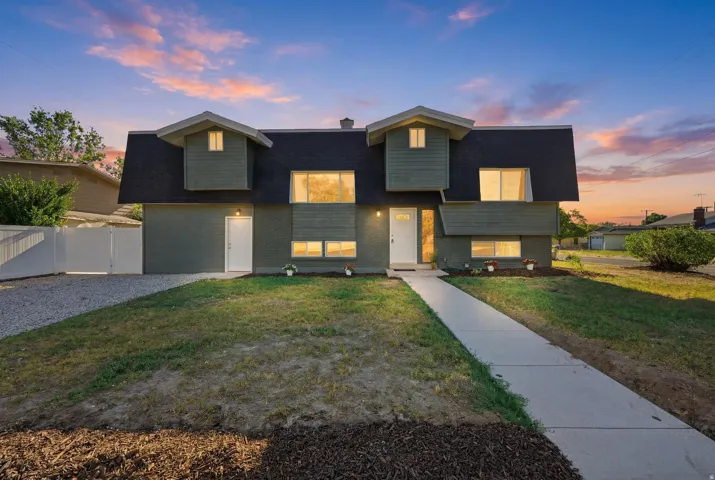 Contemporary split-level residence featuring a dark shingle roof and a muted green exterior finish