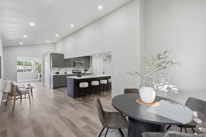 Open-concept living space featuring wood-finish flooring, recessed lighting, and vaulted ceilings