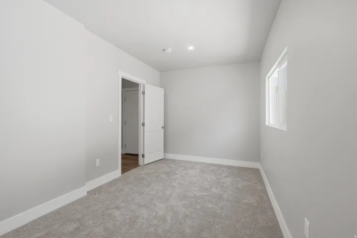 Carpeted room featuring a white interior door, a single window, recessed lighting, and light gray walls with white baseboards
