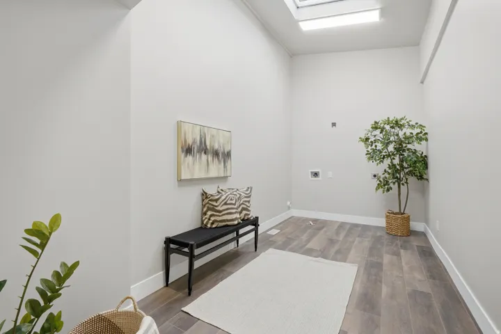 Utility room featuring wood-finish flooring, a skylight, white baseboards, and appliance hookups