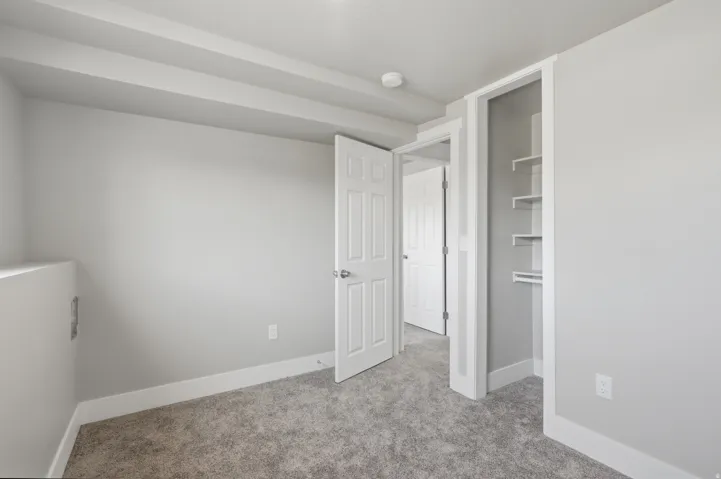 Interior space featuring light gray walls, gray carpet, white baseboards, and white ceiling trim