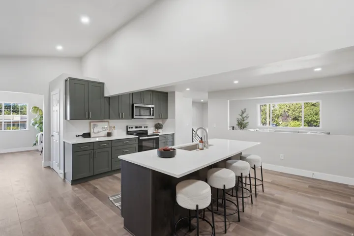 Modern kitchen featuring dark cabinetry, stainless steel appliances, a white subway tile backsplash, and a large center island with a white countertop and integrated sink