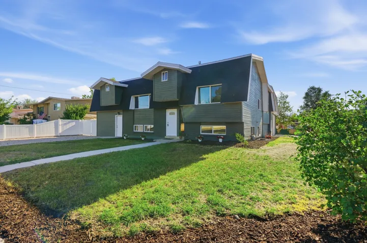Gambrel roofline property featuring dark green siding, white entry door, and dormer windows